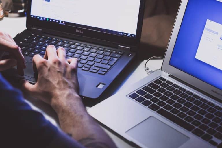 a man is typing on his laptop computer