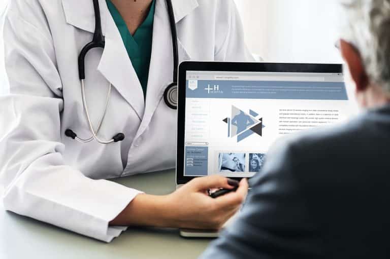 a doctor is talking to a patient in front of a laptop