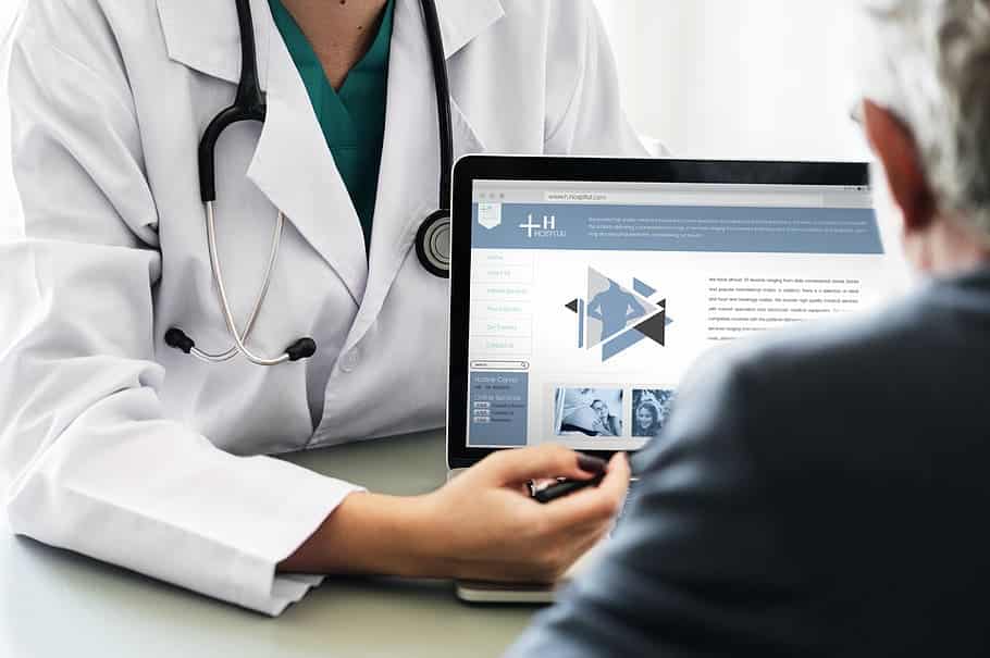 a doctor is talking to a patient in front of a laptop