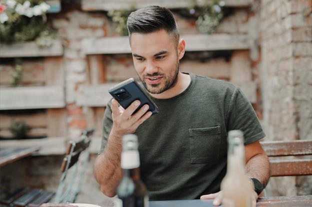 man in gray crew neck long sleeve shirt holding black smartphone