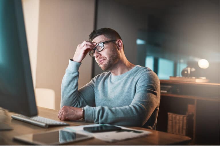 a man sitting at a desk with his head in his hands