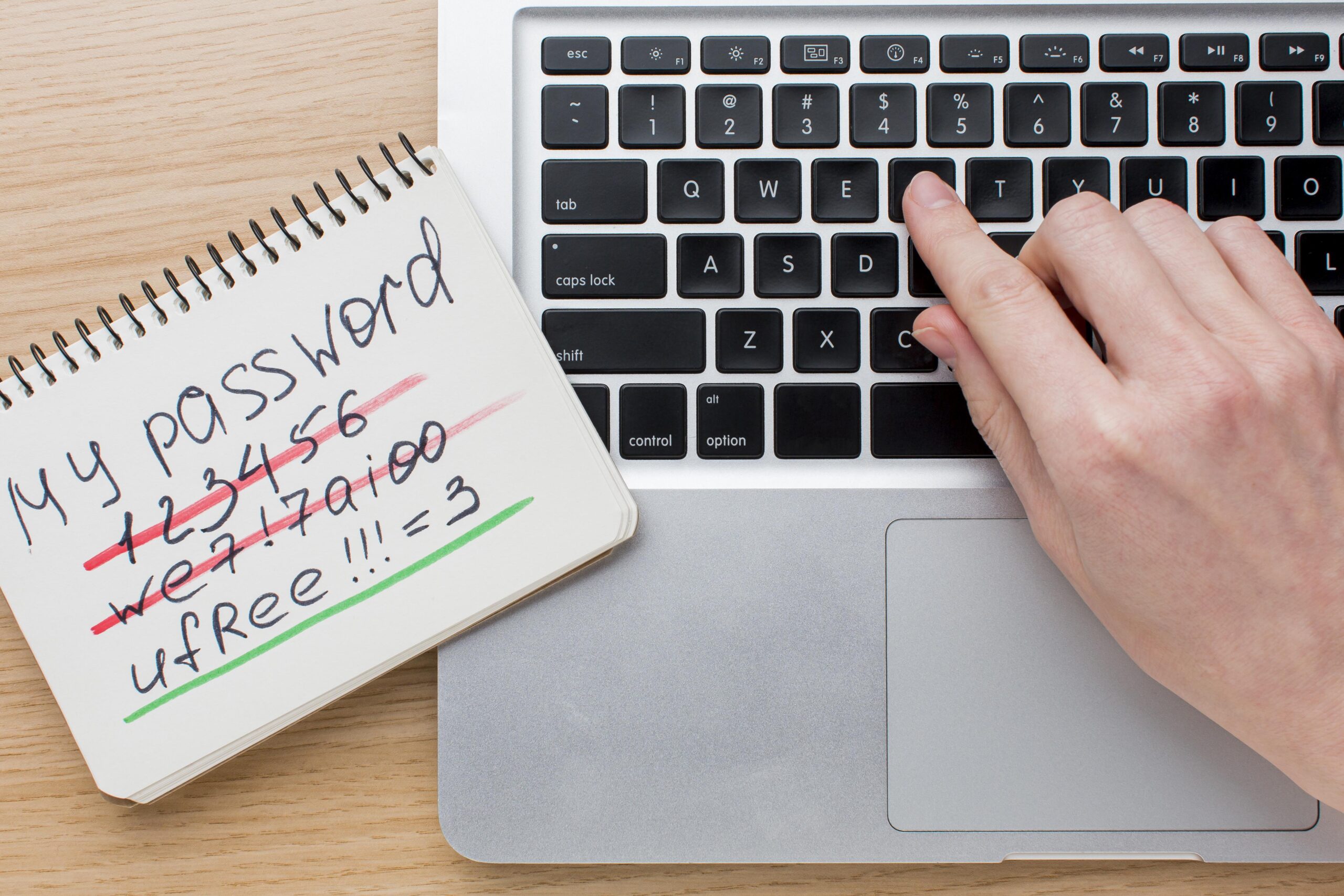 a person typing on a laptop keyboard with a note pad