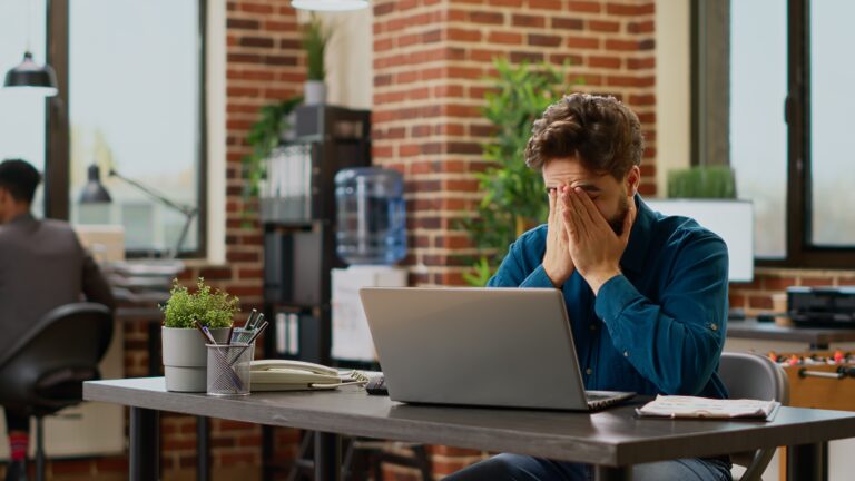 a man sitting at a table with a laptop in front of him