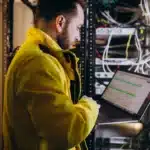 a man standing in front of a server holding a laptop