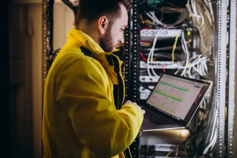 a man standing in front of a server holding a laptop