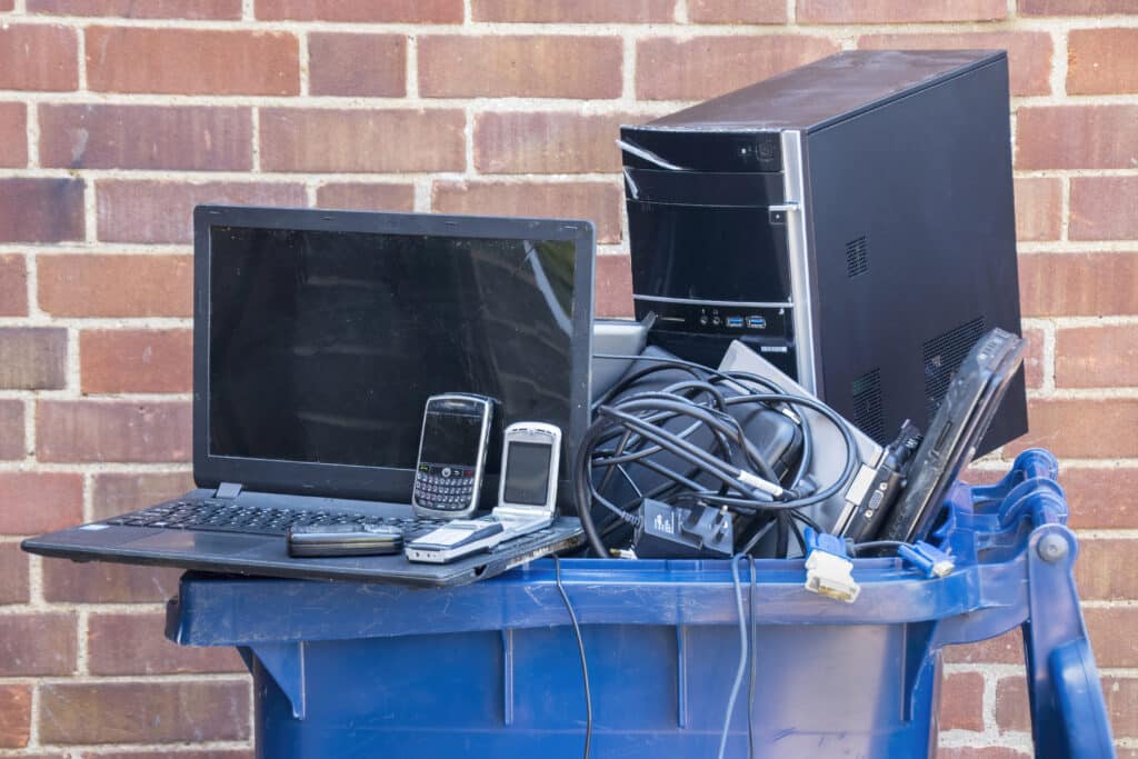 a blue trash can with a laptop computer and other electronics in it