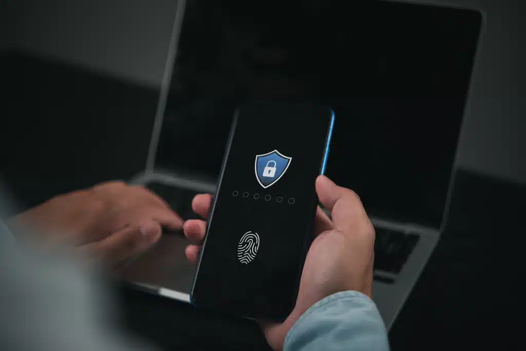 a person holding a cell phone and a laptop