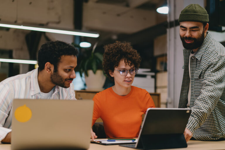 a group of people sitting around a table with laptops