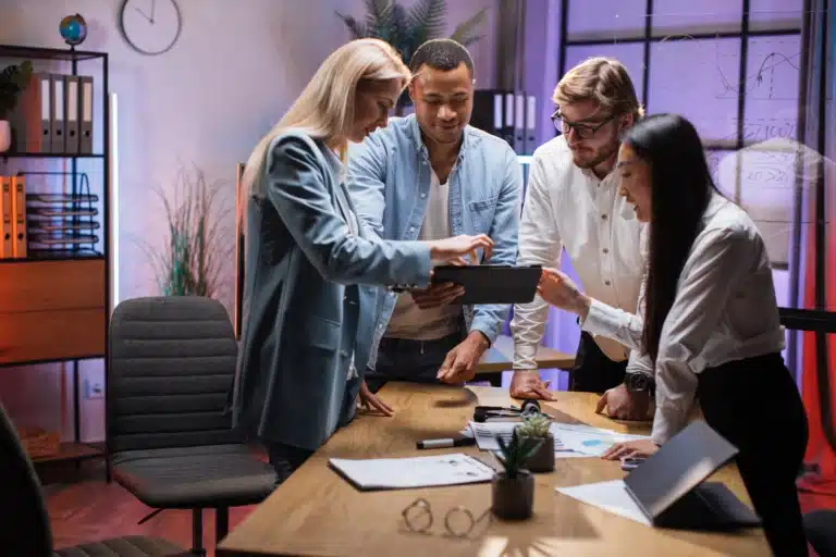 a group of people standing around a wooden table