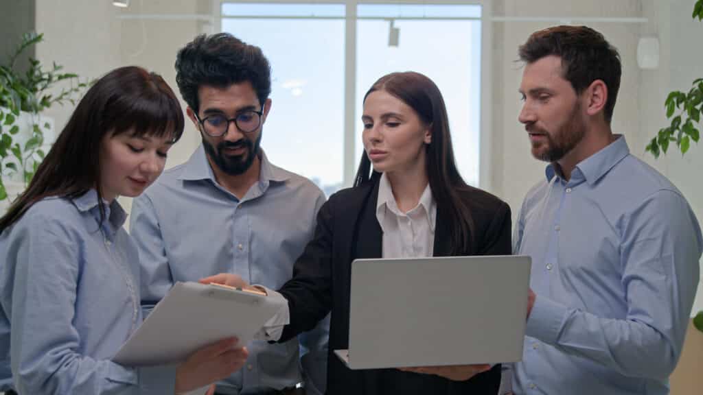 a group of people standing around a laptop computer